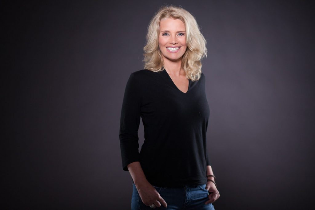 Portrait einer lächelnden blonden Frau im schwarzen Oberteil vor dunklem Studiohintergrund – Fotostudio Hamburg City Nord
